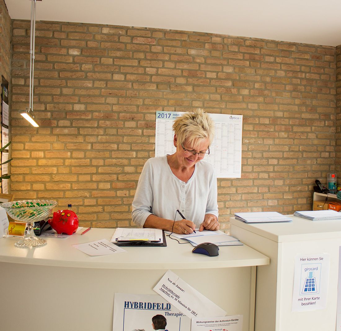 Impressionen / Einblicke - Rezeptionistin empfängt Patient freundlich und gut gelaunt | Physiotherapie & Heilpraktik in Lübbecke